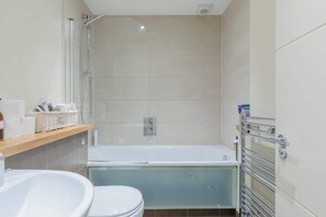A bathroom with a bathtub, toilet, and shower. - Tranquil and Homely Flat in Stoke Newington (Greater London)