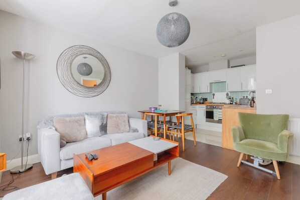 A modern living room with a sofa, coffee table, and a dining area with chairs.