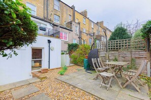 A residential area with a patio, wooden furniture, and a white building. - Tranquil and Homely Flat in Stoke Newington (Greater London)