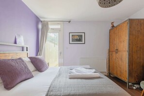 Une chambre comprenant un lit, une armoire en bois, un radiateur et une porte donnant sur un espace extérieur.