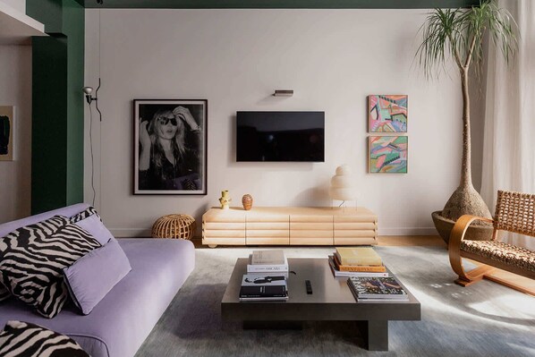 Un salon moderne avec un canapé, une table basse et un téléviseur fixé au mur.
