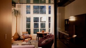 A cozy living room with a large window, a round table, a sofa, and a TV stand.
