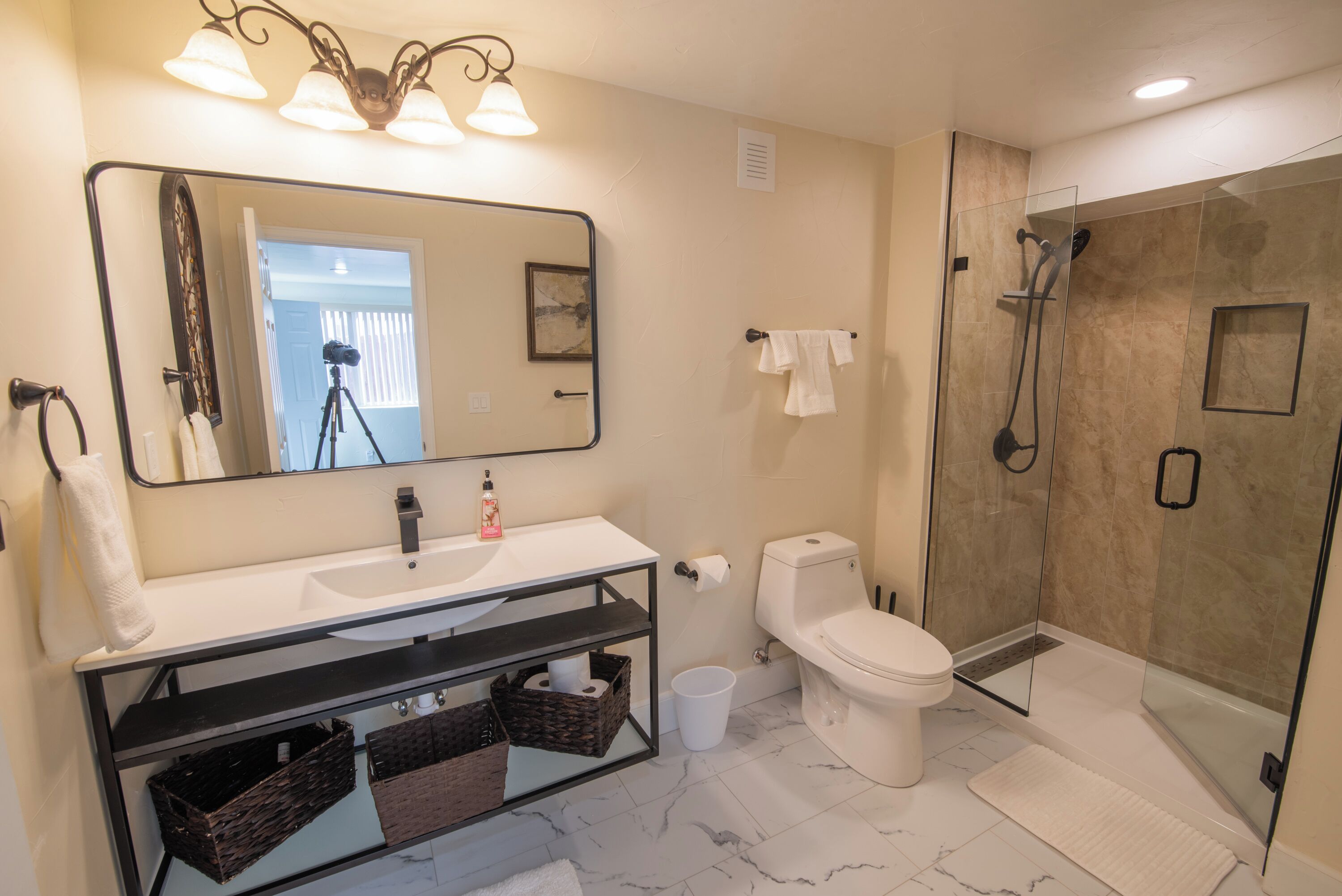 A modern bathroom with a large mirror, white sink, and a glass-enclosed shower.