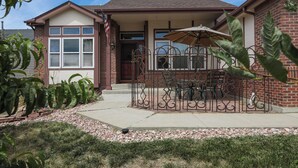 A two-story house with a covered patio area featuring a metal fence and a table with chairs. - Tuscan Hills Hideaway - 6 Bedrooms, 14 beds, Up to 25 people (Westminster)