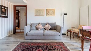 A living room with a grey sofa, two framed maps on the wall, a patterned rug, and a wooden table. - Casa Melzo, with garage near Porta Venezia (Milano)