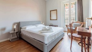 A neatly made bed with white linens, a bedside table with a lamp, a wooden chair, and a dining table with chairs. - Casa Melzo, with garage near Porta Venezia (Milano)