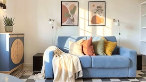 Ein Wohnzimmer mit blauem Sofa, einem gemusterten Boden und Wandbildern.