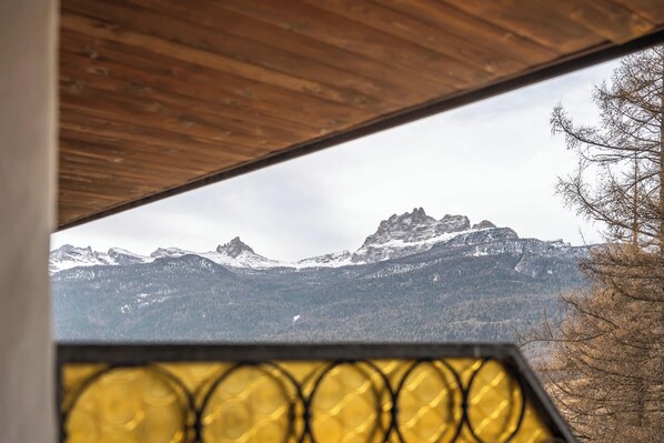 A view of snow-capped mountains through a window with a wooden ceiling.