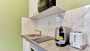 Een compacte keuken met een ingebouwde magnetron, een koffiezetapparaat en een broodrooster.