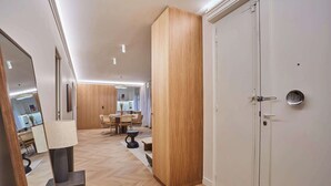 Un intérieur moderne avec un plancher en bois, un coin repas doté d’une table ronde et une porte blanche avec une poignée ronde.