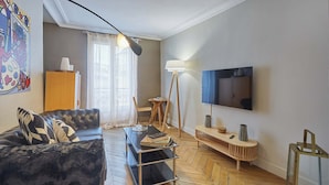 Een moderne woonkamer met een bank, een salontafel, een vloerlamp, een televisie en een houten vloer.