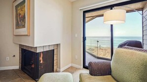 Una sala de estar con chimenea, un ventanal con vista a la playa y una zona de estar cómoda.