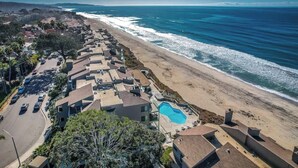 Zona residencial costera con casas, piscina y playa.
