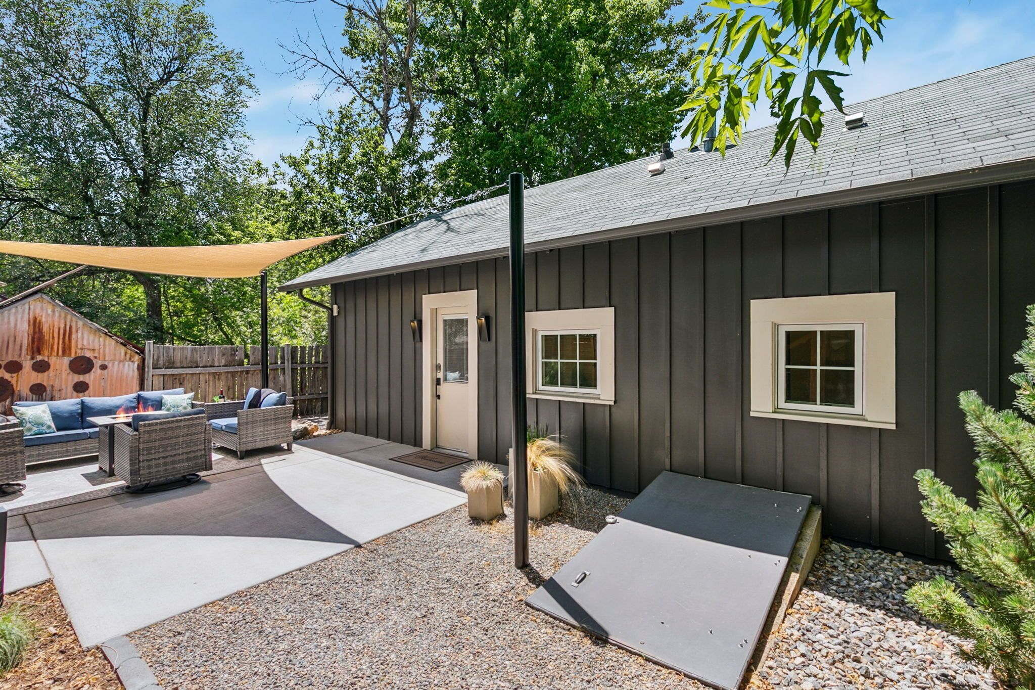 Eine überdachte Terrasse mit Gartenmöbeln, eine kleine Gartenhütte und ein Gebäude mit Fenstern.