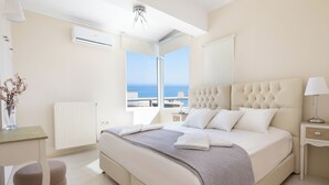 Ein modernes Schlafzimmer mit einem großen Bett, einem Nachttisch, einer Lampe und Meerblick.