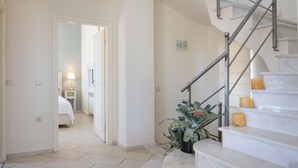 Ein Hotelkorridor mit einer Marmortreppe, einem Blumentopf und einem Bett im angrenzenden Zimmer.