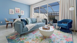 Un salon avec un canapé bleu, un fauteuil bleu, une table basse et un tapis coloré.