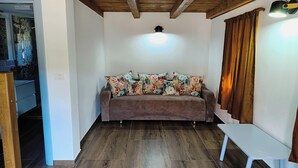 Una habitación acogedora con un sofá marrón, una mesa blanca y un techo de madera.