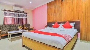 Habitación de hotel con una cama grande, un sofá, una mesita y un panel de pared de madera.