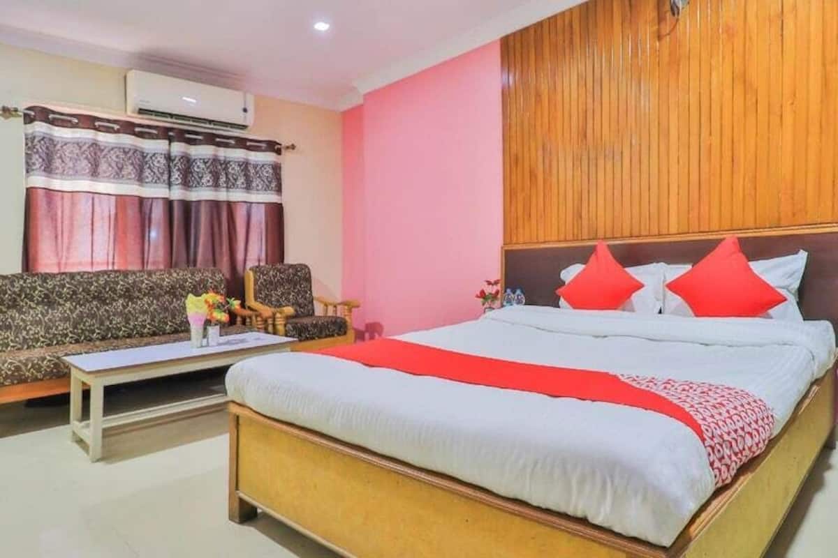 Habitación de hotel con una cama grande, un sofá, una mesita y un panel de pared de madera.