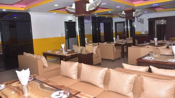Un restaurante con varias zonas de estar, incluyendo sofás y mesas, y ventiladores de techo.