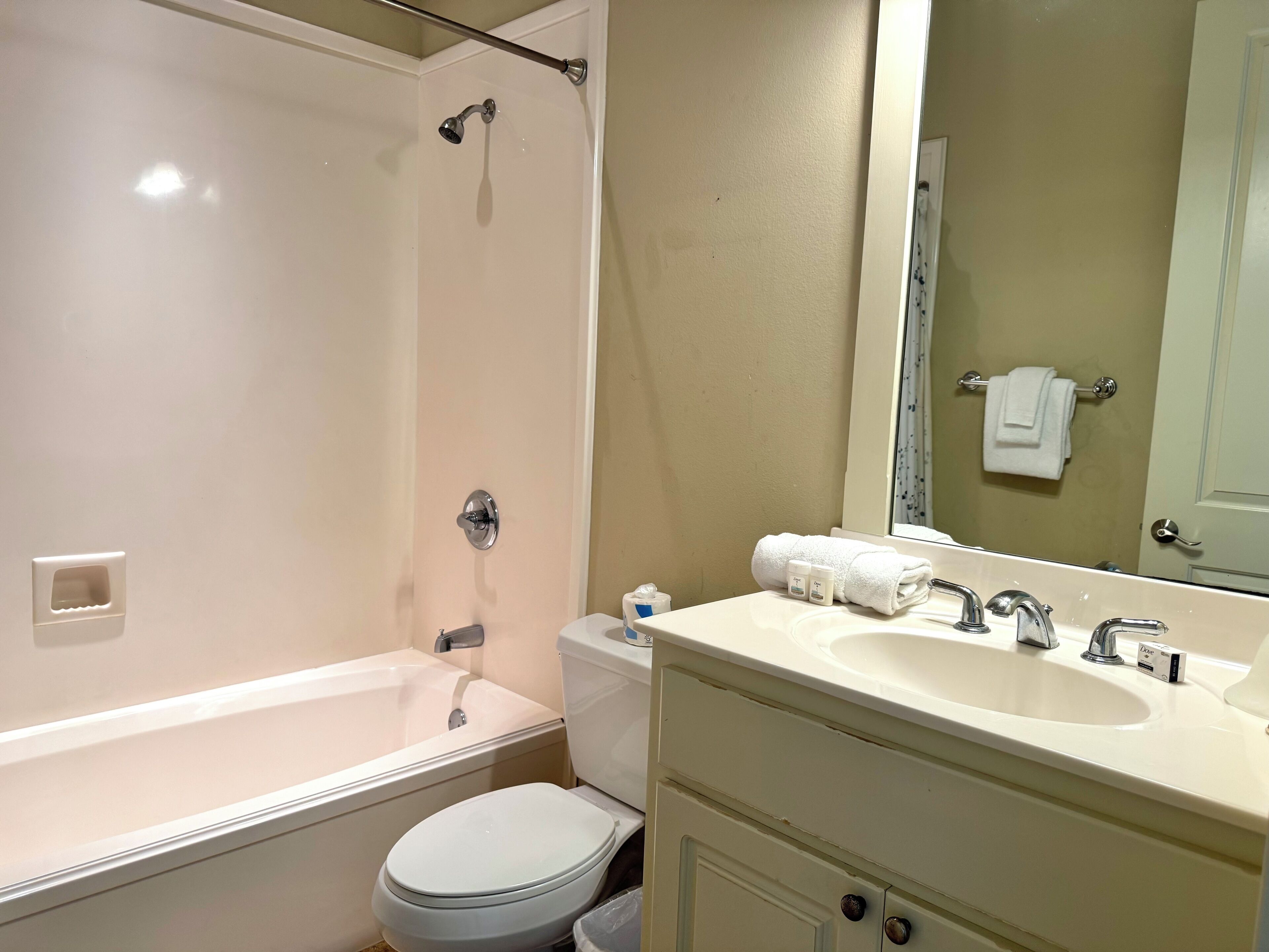 Un bagno con vasca, water e lavabo con specchio.