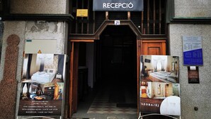 Une entrée d’immeuble avec une enseigne indiquant la réception, une autre avec le numéro 16, et deux affiches publicitaires pour des meubles.