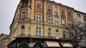 Un bâtiment historique doté d’un dôme central, de nombreuses fenêtres et d’une entrée au niveau du sol, reconnaissable à une enseigne.