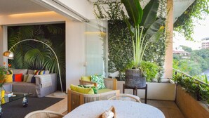 Una sala de estar moderna con un sofá, sillas, una mesa de centro y una planta grande en maceta.