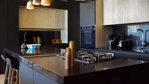 Una cocina moderna con una isla grande, armarios negros y una campana extractora de acero inoxidable.