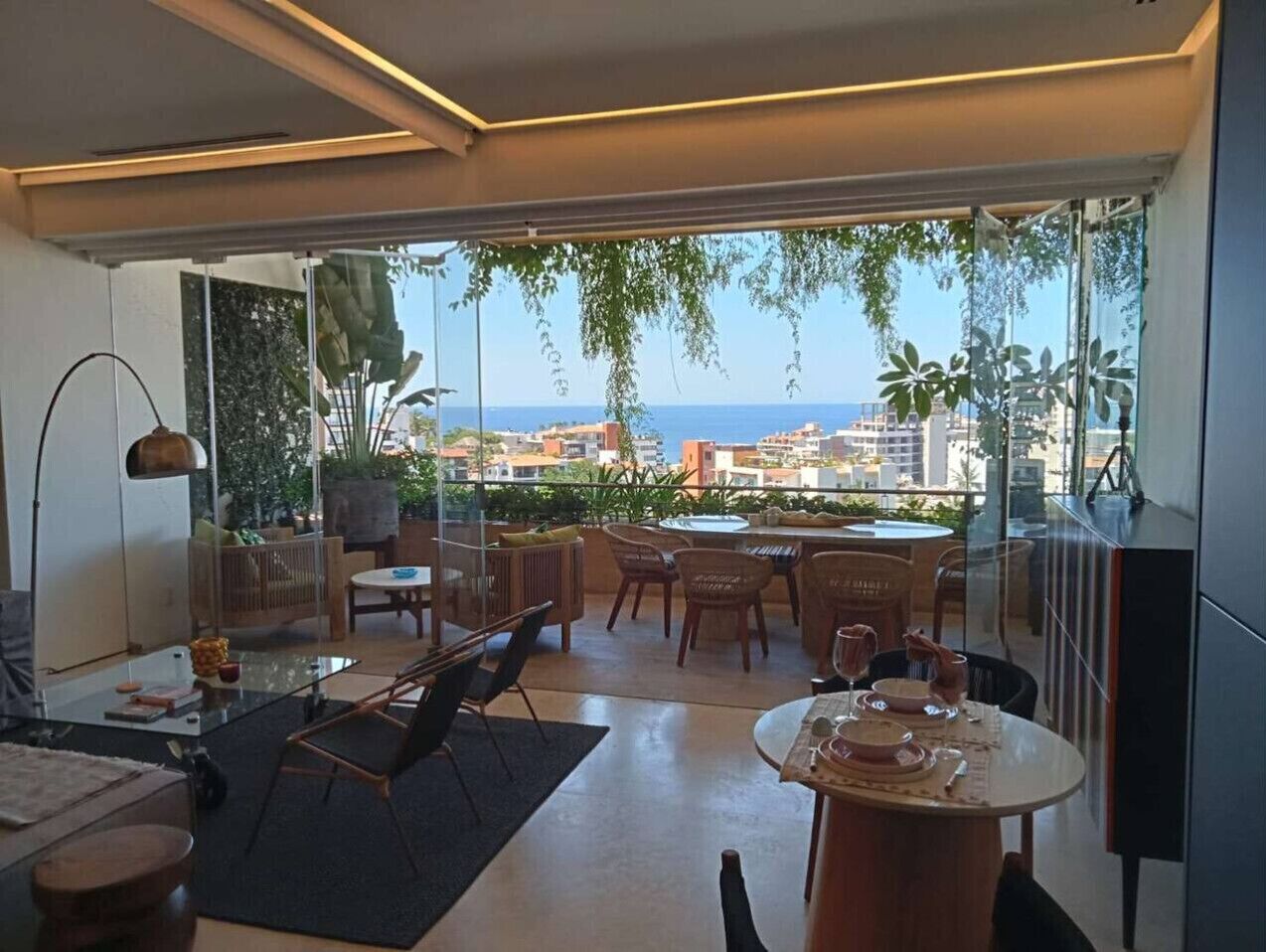 A modern living room with a glass door leading to a balcony with a city view.