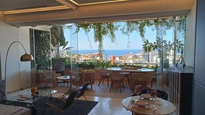 Una sala de estar moderna con un ventanal que da a un balcón con vistas a la ciudad.