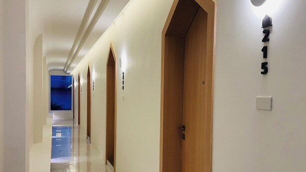 A hotel corridor with wooden doors, a marble floor, and a number sign '215' on the wall. - Minitel at hatyai (Hat Yai)