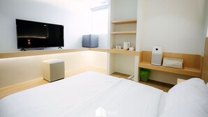 A modern hotel room with a large bed, a flat-screen TV mounted on the wall, a small refrigerator, and a wooden shelf with toiletries. - Minitel at hatyai (Hat Yai)