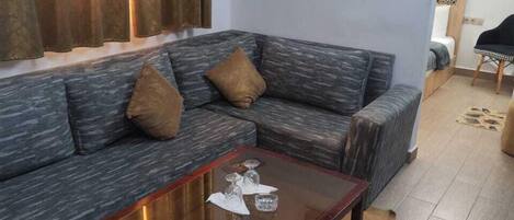 Una sala de estar con un sofá gris, una mesa de centro de vidrio y un cuadro en la pared.