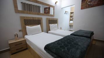 A hotel room with two beds, a wooden nightstand, a mirror, and a painting on the wall.