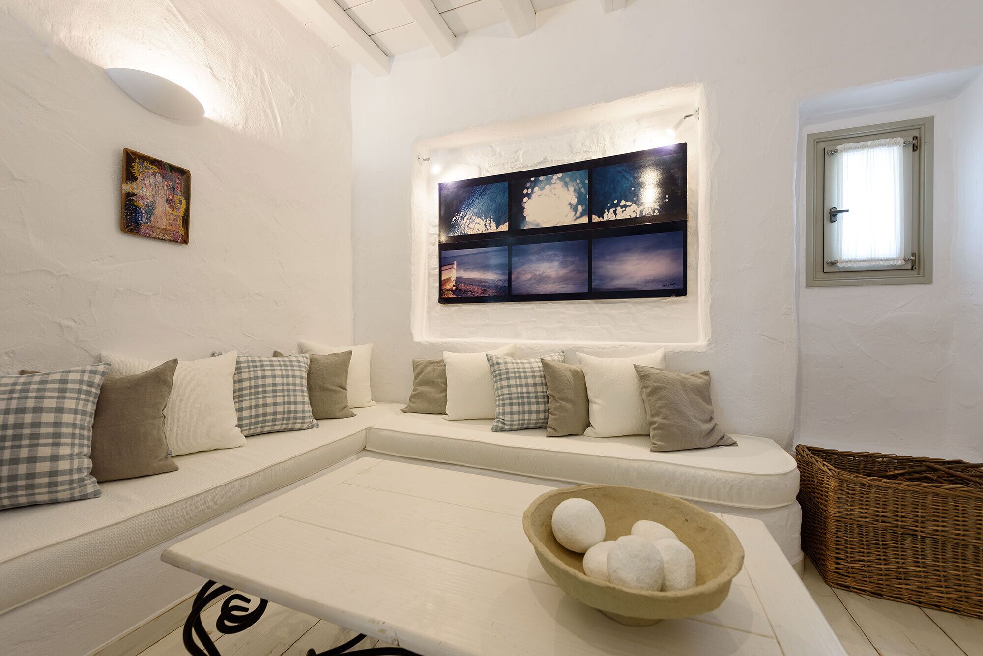A modern living room with a white sofa, a coffee table, and a wall-mounted artwork.