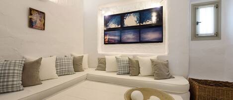 A modern living room with a white sofa, a coffee table, and a wall-mounted artwork.