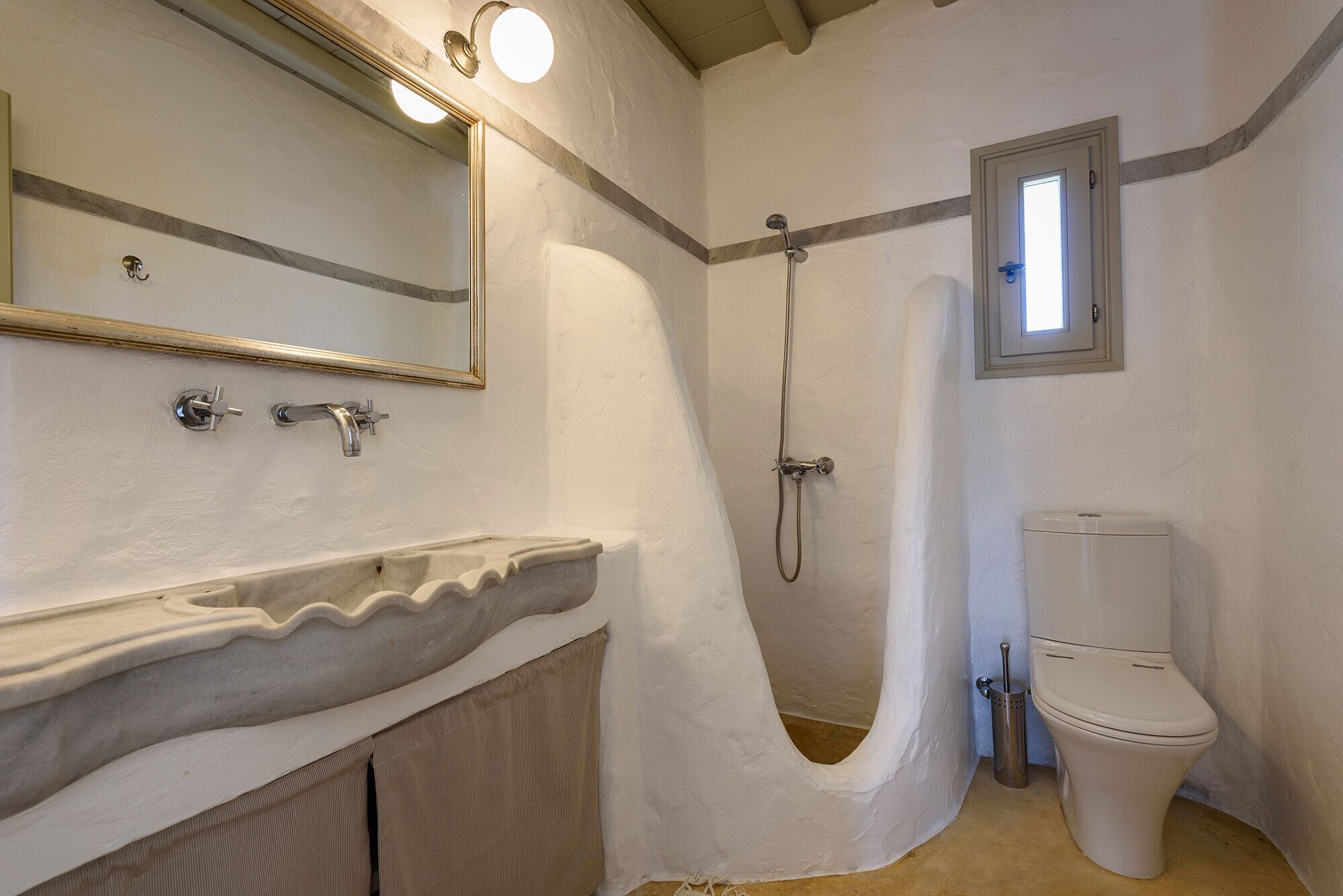 A bathroom with a sink, mirror, shower, and toilet.