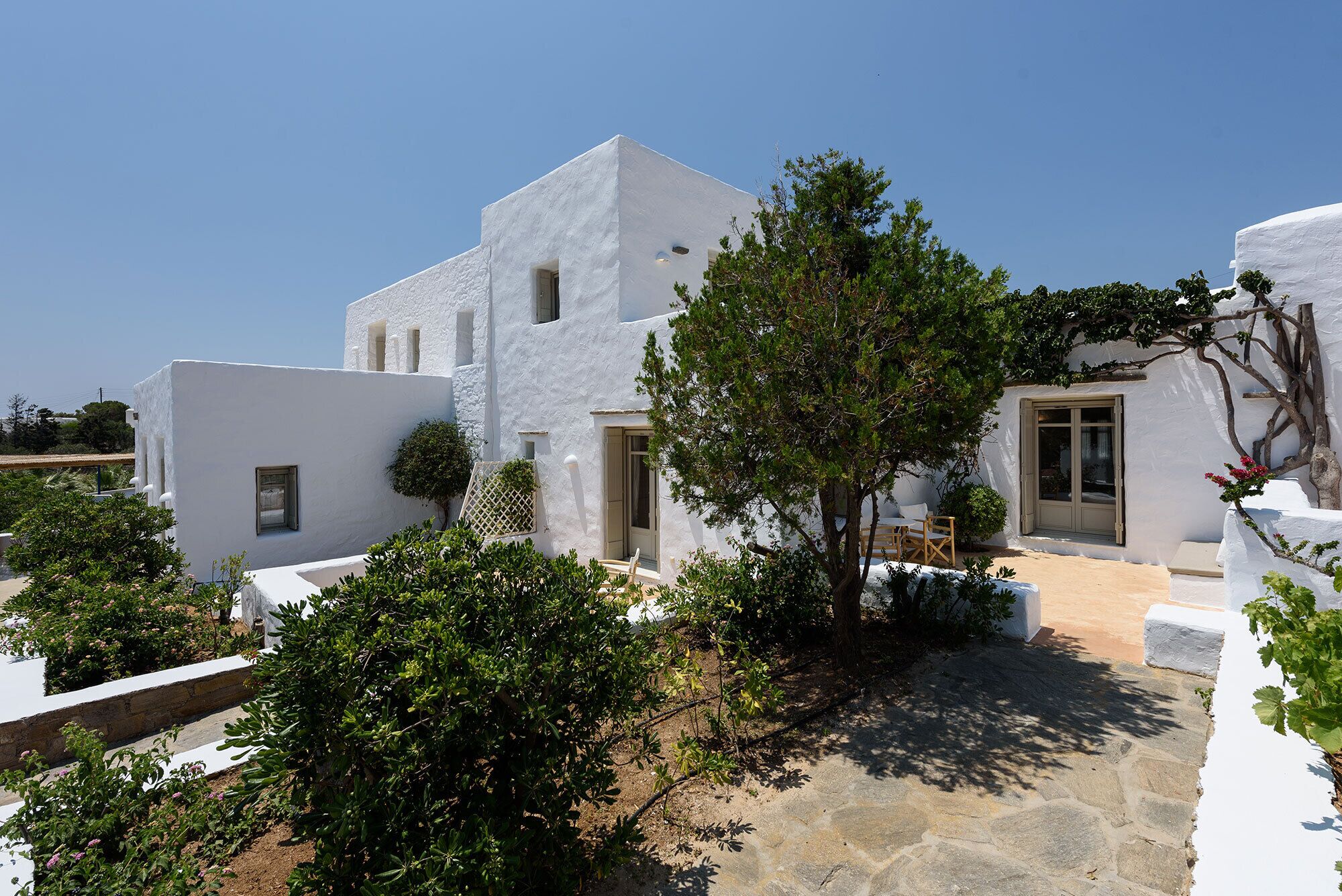 A white building with a stone pathway and greenery.