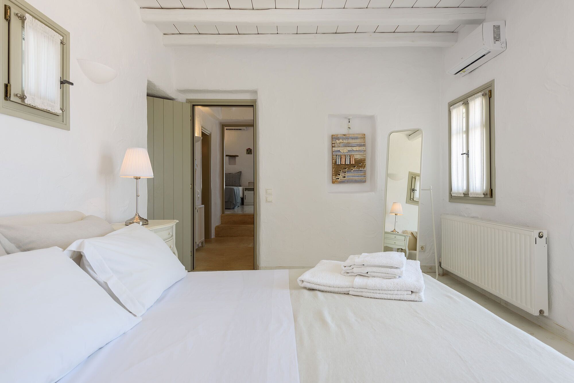 Une chambre d’hôtel avec un lit, une table de chevet, une lampe, un radiateur et une fenêtre avec des rideaux.