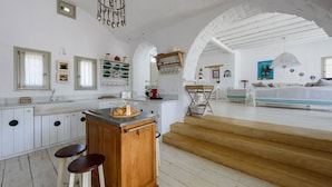 A spacious kitchen with a central island, wooden stools, and a chandelier. - Villa Vinea Paros (Paros)