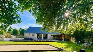 A house with a stone exterior, a covered patio, and a lawn with outdoor furniture.