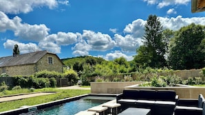 A swimming pool with lounge chairs and a stone building in the background.