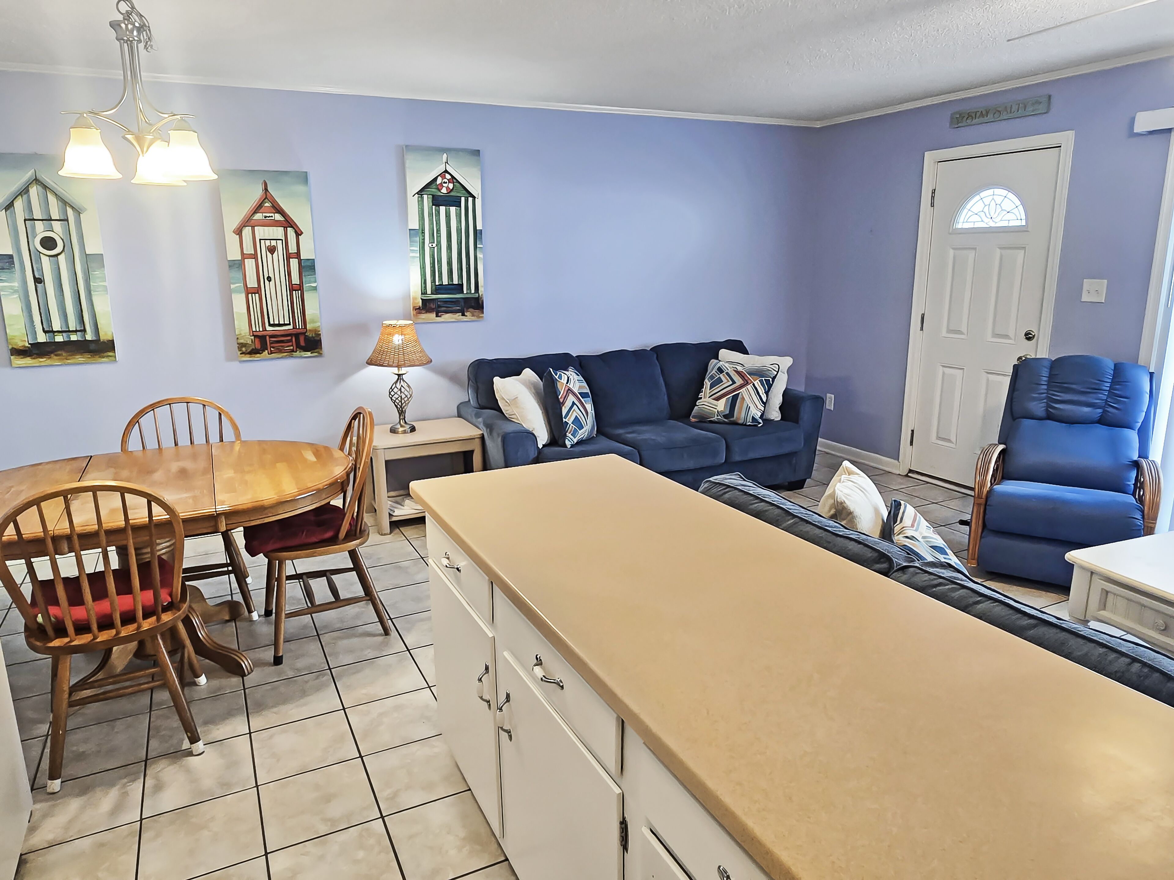 Un salón con una mesa de comedor, sofá azul y sillón azul.