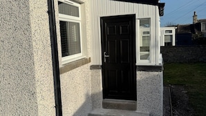 A house with a white exterior, a black front door, and a small porch area.