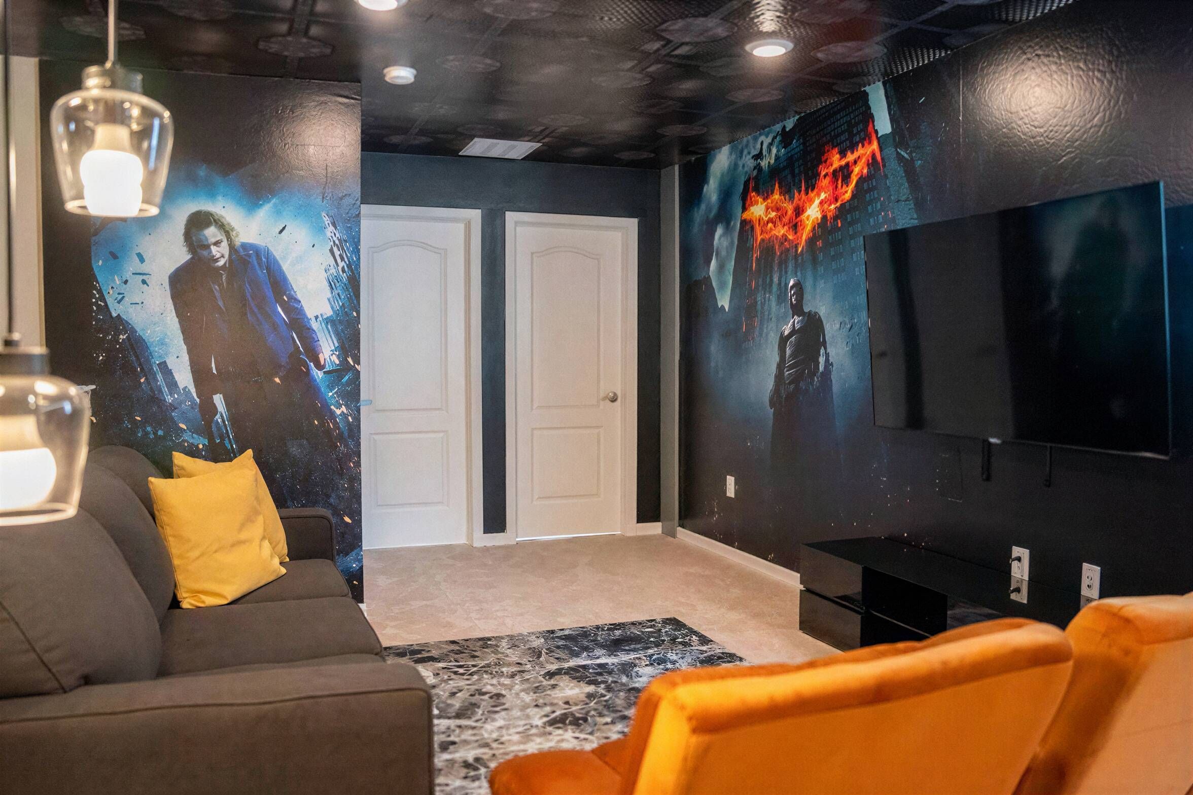 Una sala de cine en casa con un televisor de pantalla plana grande, un sofá y piso alfombrado.