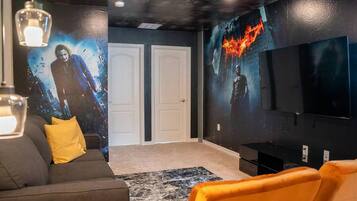 Una sala de cine en casa con un televisor de pantalla plana grande, un sofá y piso alfombrado.