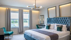Un dormitorio moderno con una cama grande, un cabecero azul y vistas al exterior a través de la ventana.