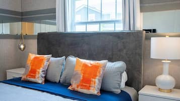 Habitación de hotel con una cama grande, una mesita de noche, una lámpara y una ventana con vistas a un edificio.